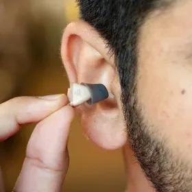 Invisible hearing aid being placed discreetly